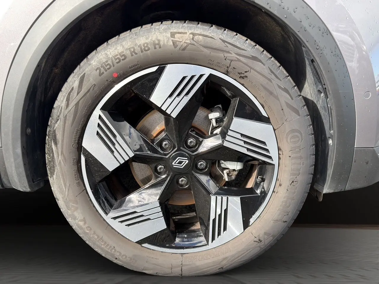 Gros plan sur la roue avant droite du Renault Symbioz gris clair, mettant en valeur la jante noire et argentée au design géométrique.