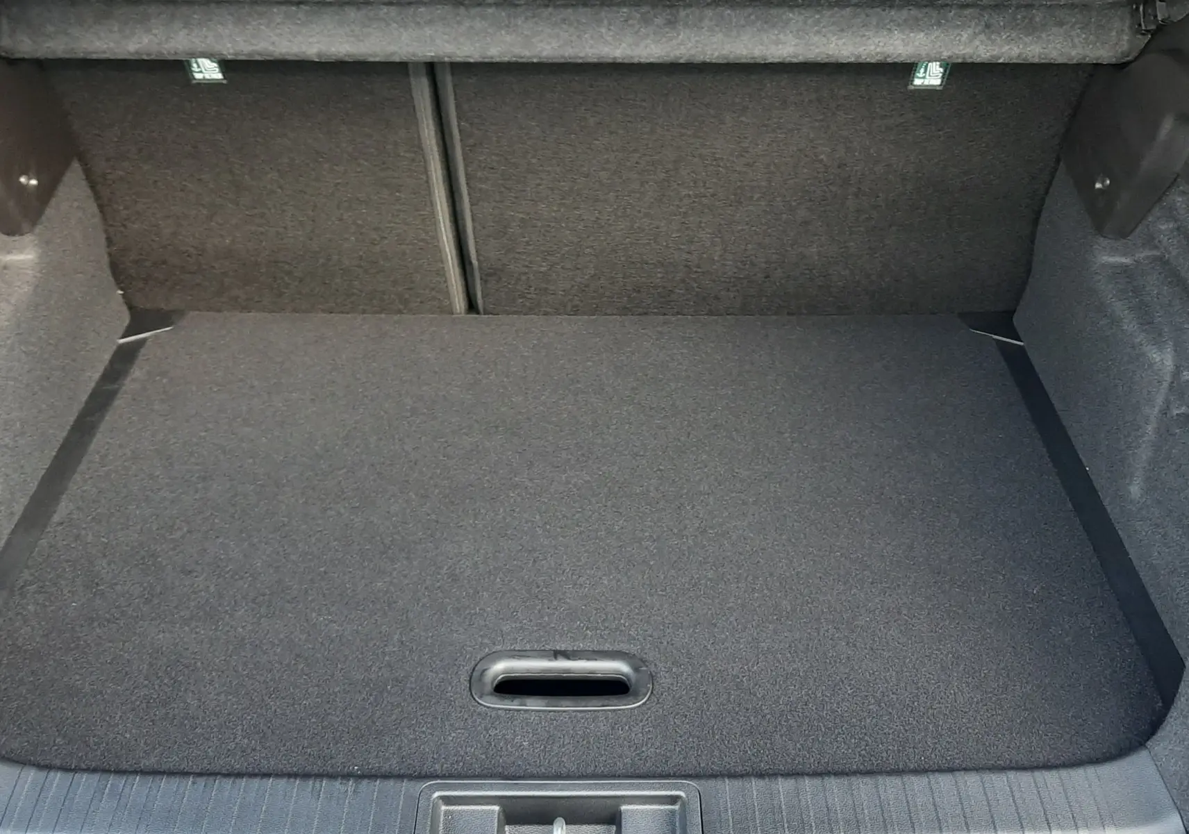 Coffre ouvert du Renault Captur 2025 gris Cassiopée, vue intérieure montrant le plancher plat et le revêtement noir.