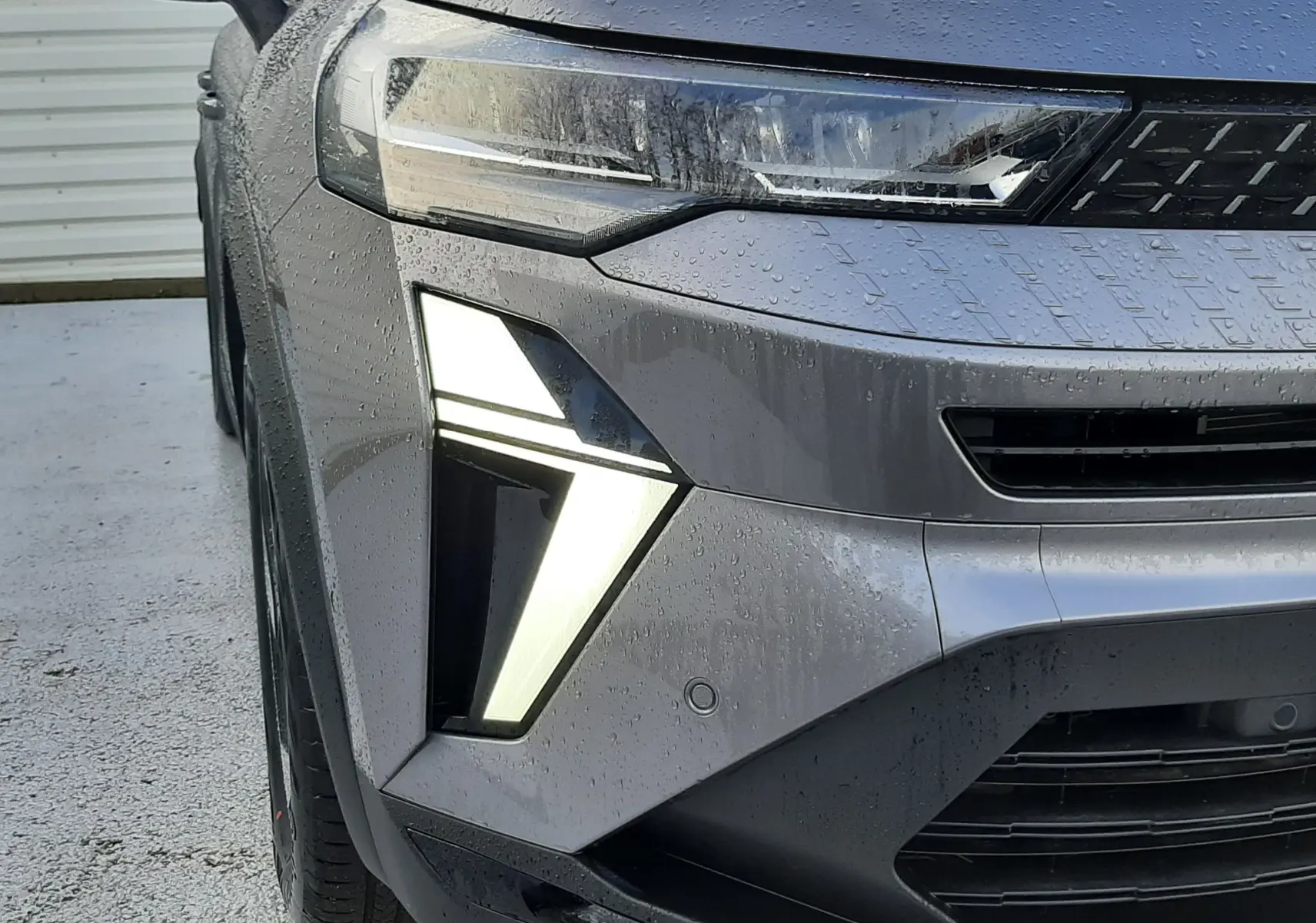 Gros plan sur l'avant gauche du Renault Captur gris Cassiopée, mettant en valeur ses phares LED distinctifs allumés.