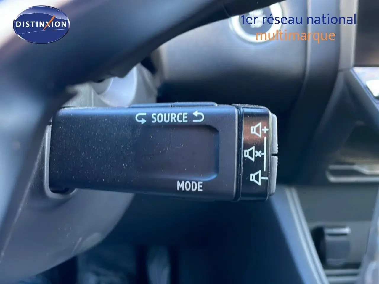 Gros plan sur la commande au volant droite du Renault Captur rouge désir métal, avec boutons source et mode visibles.