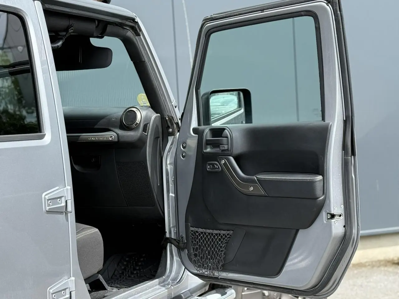 Portière avant droite ouverte d'un Jeep Wrangler Billet Silver 2019, montrant l'intérieur noir côté passager.