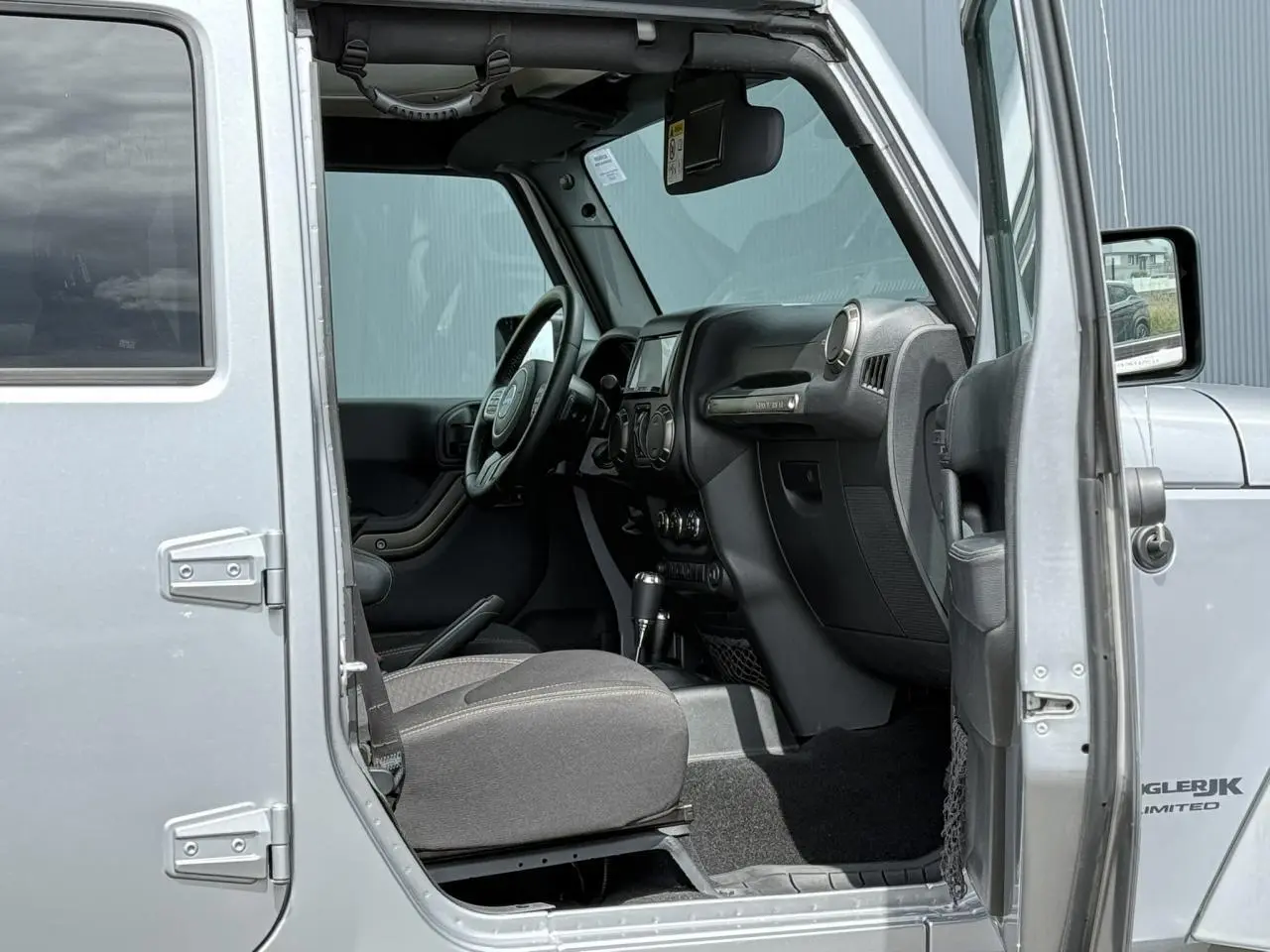 Vue intérieure côté conducteur d'une Jeep Wrangler Billet Silver 2019, mettant en valeur le tableau de bord et le volant multifonction.