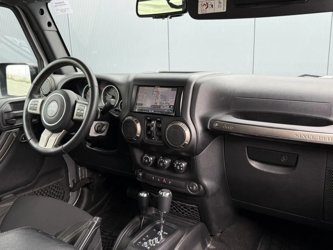 Intérieur avant du Jeep Wrangler 2019, tableau de bord noir avec écran GPS et volant multifonction visible côté gauche.