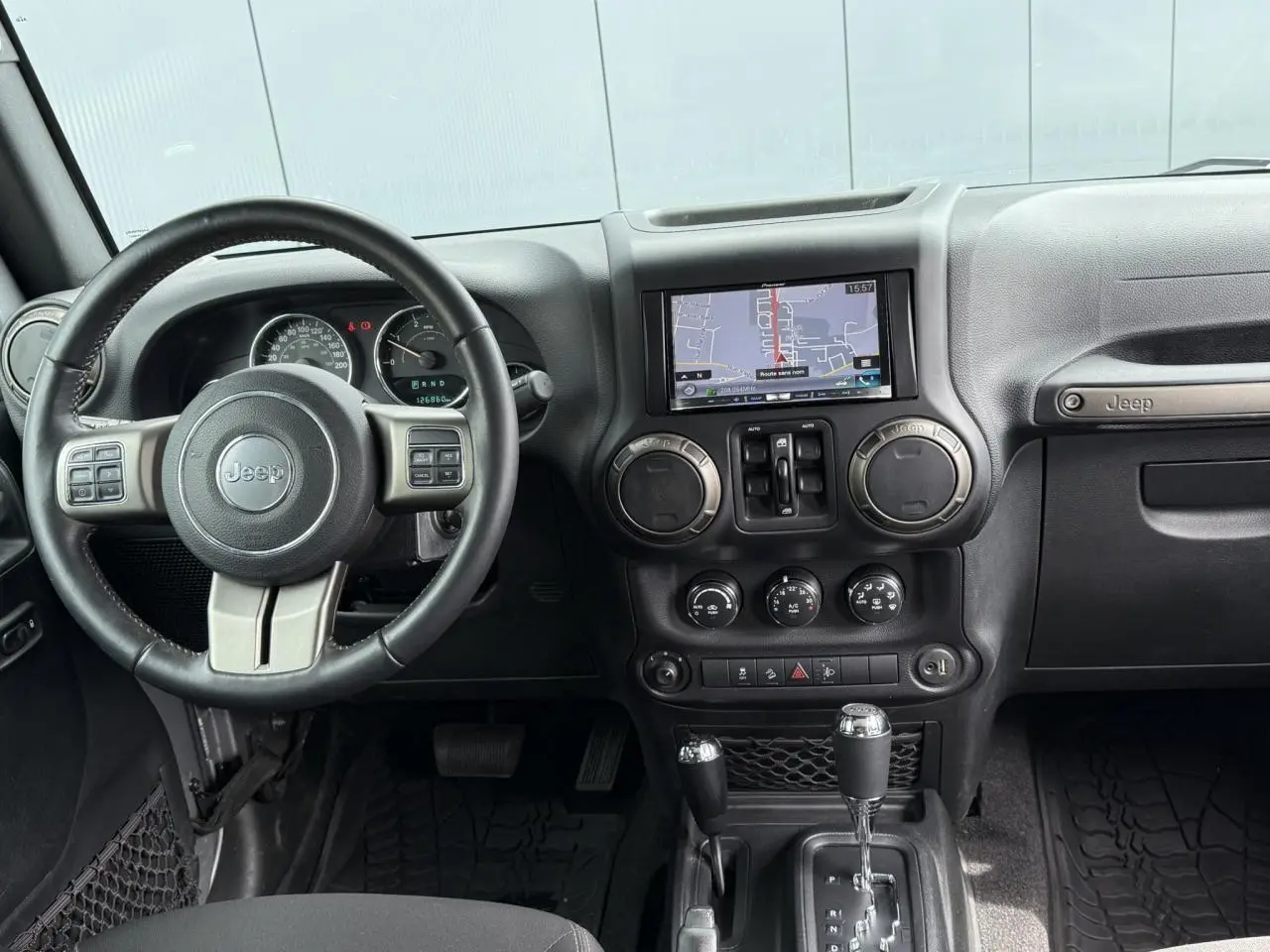 Intérieur de Jeep Wrangler 2019 vu de face, tableau de bord noir avec écran GPS et volant multifonction Jeep.