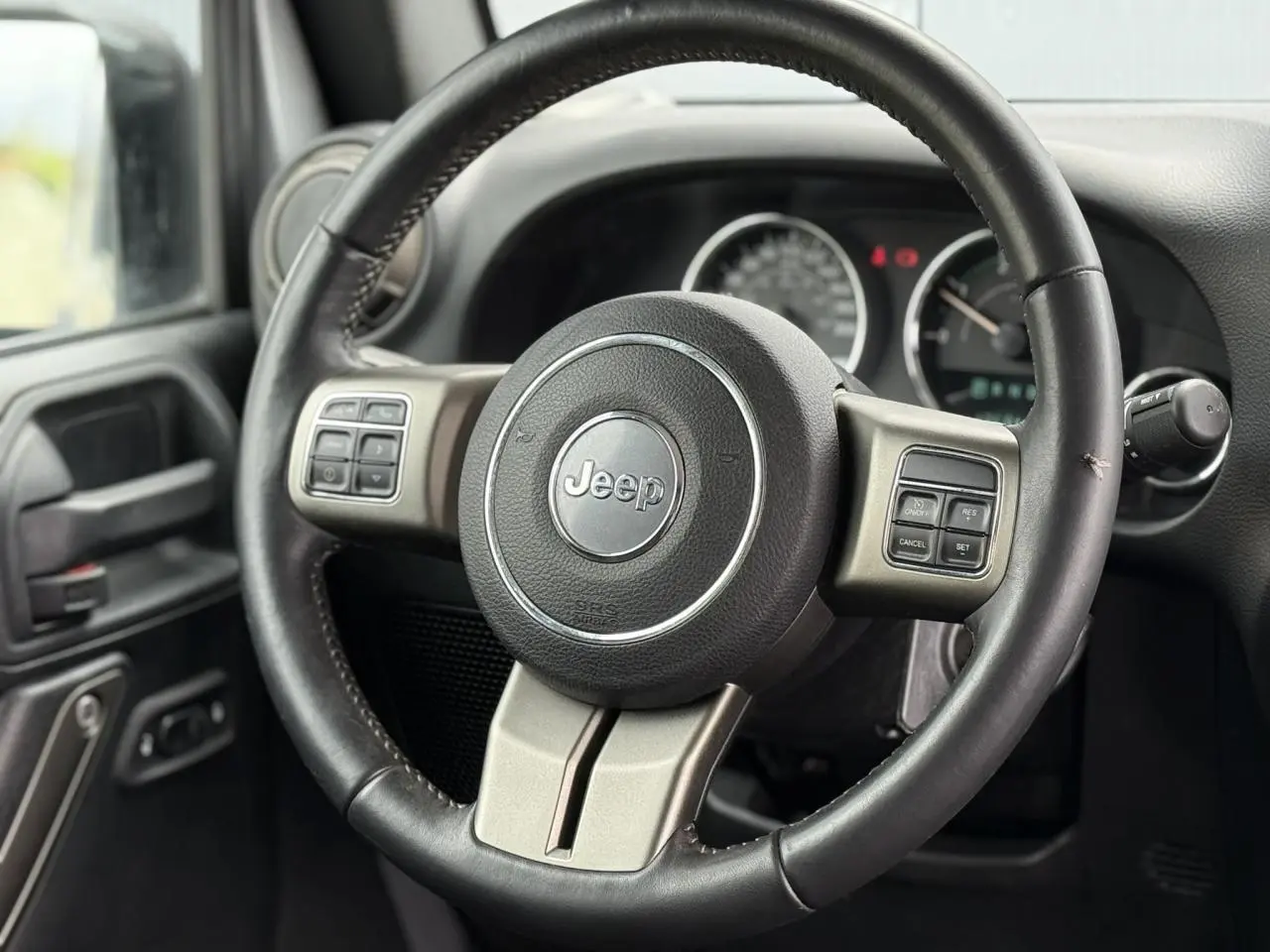 Volant multifonction Jeep Wrangler 2019 en cuir noir, vue rapprochée côté conducteur avec tableau de bord flou.