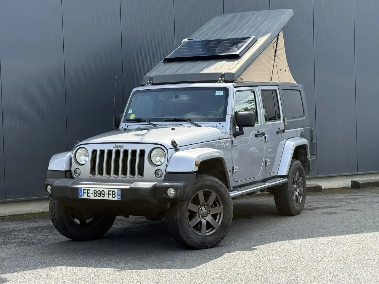 Jeep Wrangler Billet Silver vue 3/4 avant gauche avec toit relevable et panneau solaire sur le toit.