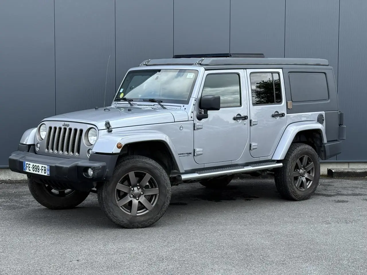 Jeep Wrangler 2.8 CRD 2019 en Billet Silver, vue 3/4 avant gauche avec toit relevable et cellule de vie noire.