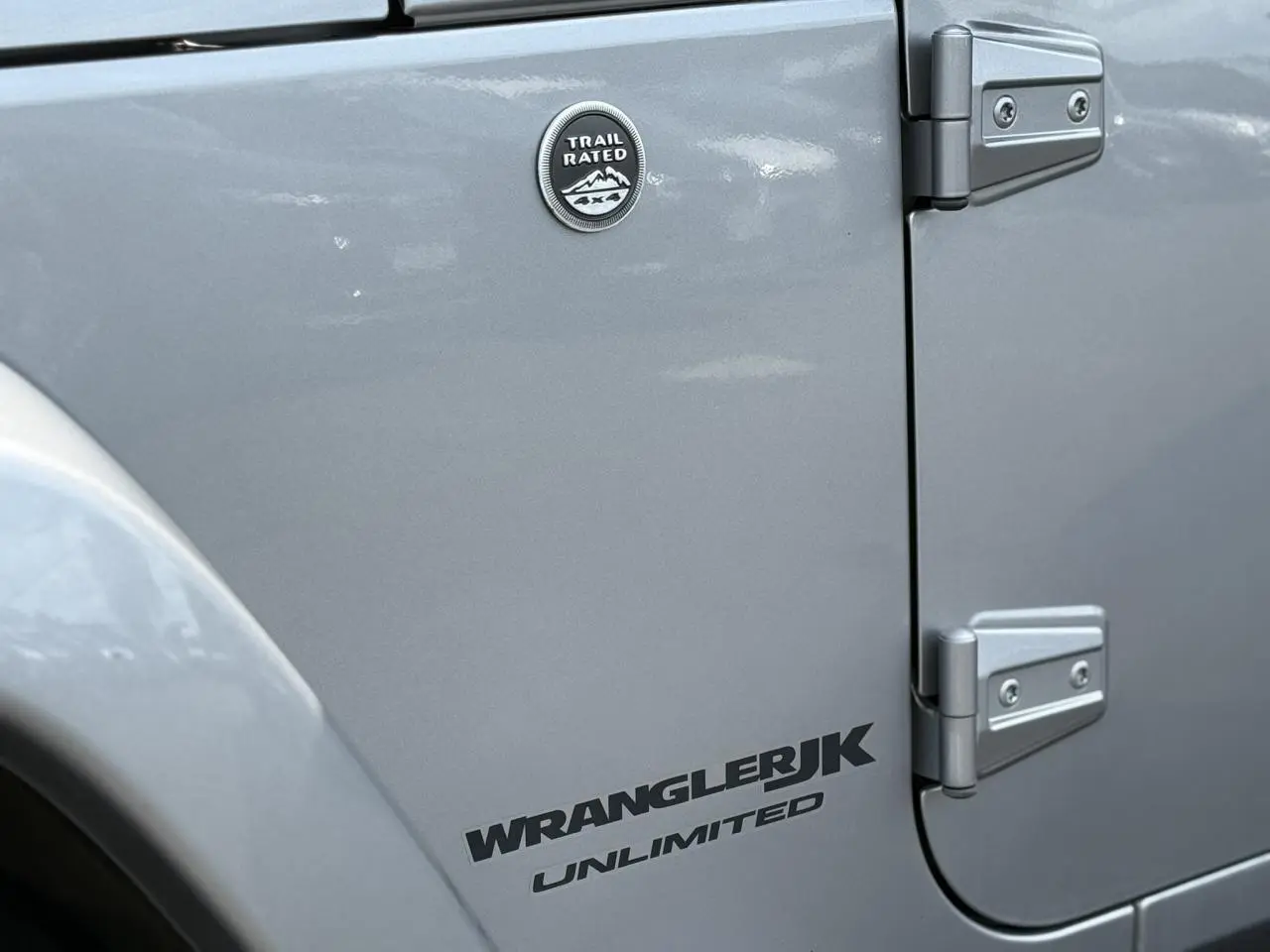 Gros plan sur la porte côté gauche d'une Jeep Wrangler JK Unlimited Billet Silver avec badge Trail Rated.
