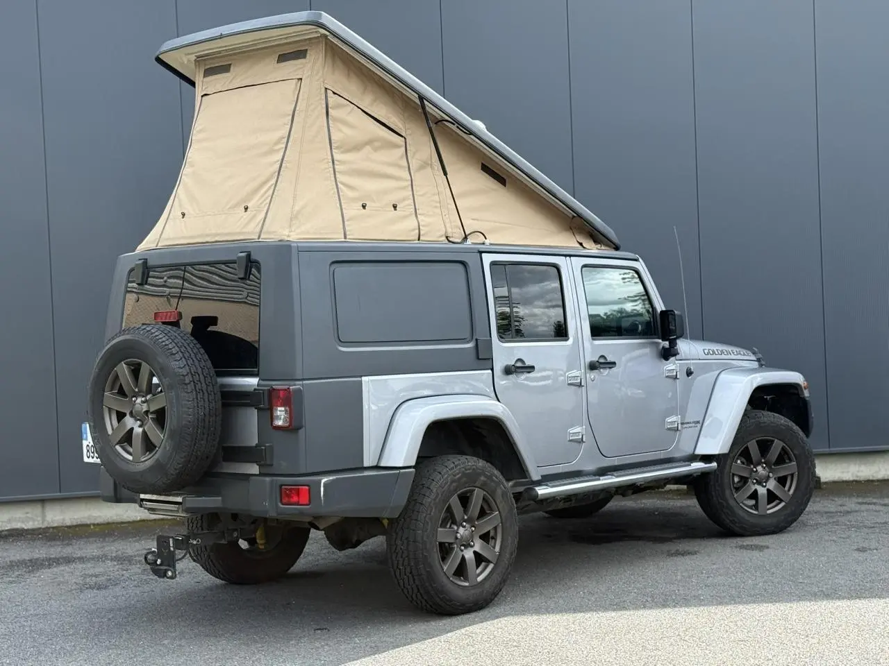 Jeep Wrangler 2.8 CRD 2019 Billet Silver vue 3/4 arrière avec toit relevable beige et cellule de vie intégrée.