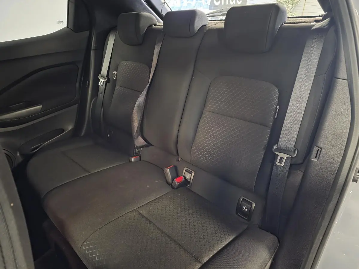 Banquette arrière noire du Nissan Juke 2023 vue de côté droit avec trois appuis-tête réglables et ceintures de sécurité.