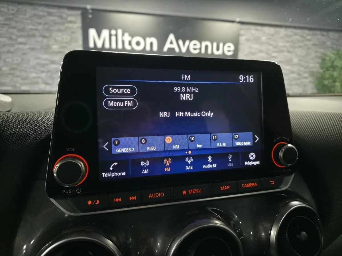 Écran tactile central du Nissan Juke 2023 affichant la radio FM NRJ, avec commandes audio et climatisation visibles.