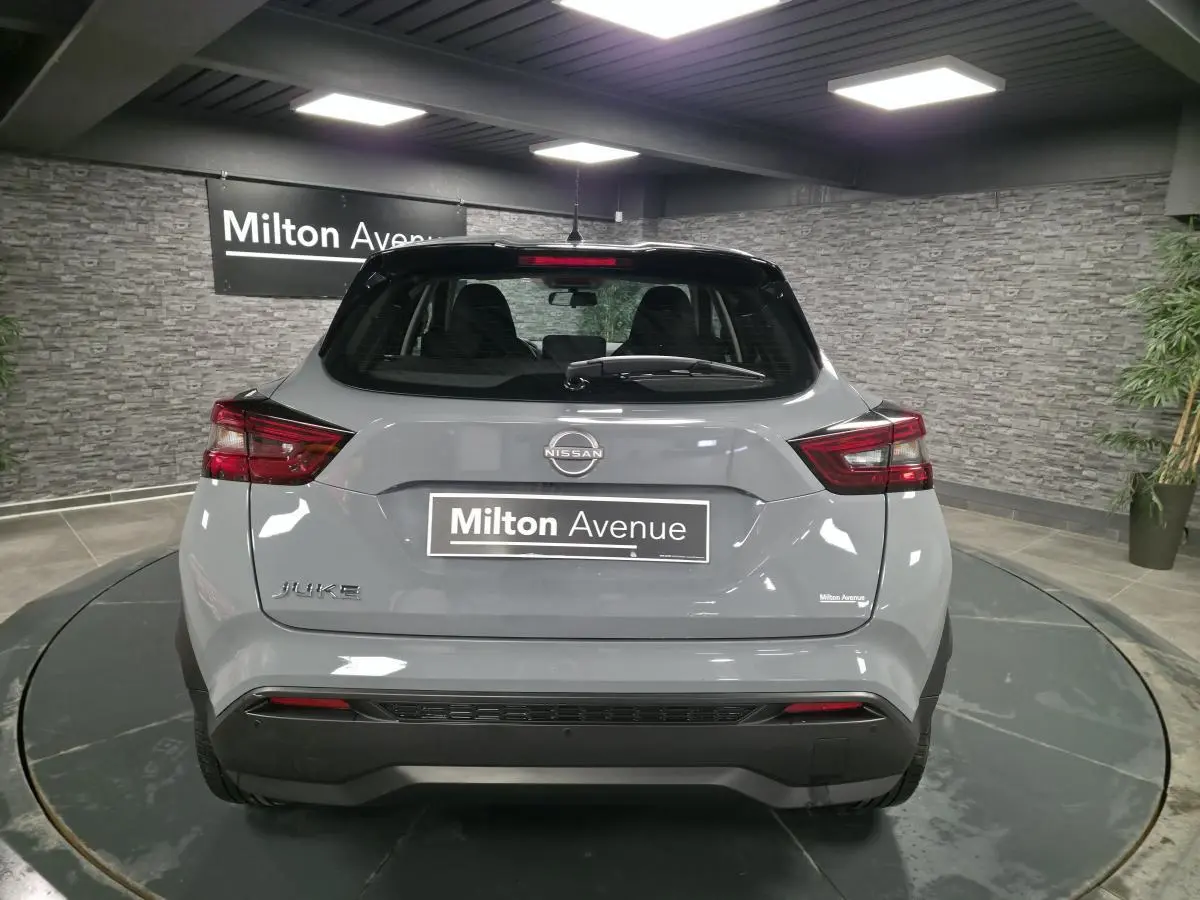 Vue arrière d'un Nissan Juke gris métallisé 2023 dans un showroom avec éclairage intérieur et panneau Milton Avenue.