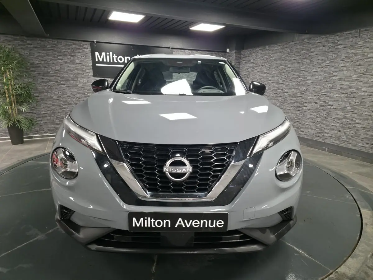 Vue frontale d'un Nissan Juke gris 2023 avec calandre noire en nid d'abeille et phares ronds distinctifs.