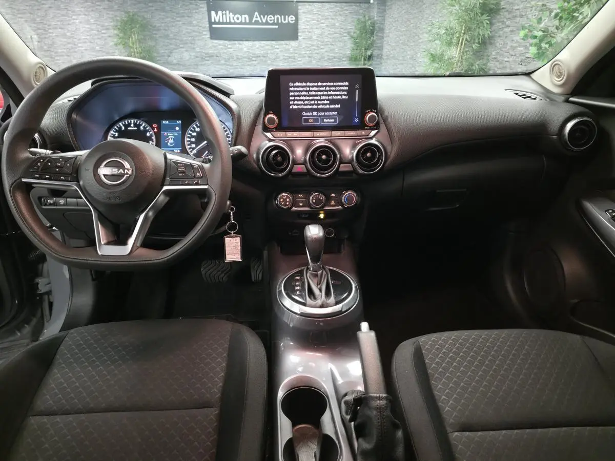 Intérieur noir du Nissan Juke 2023 vu de face, avec tableau de bord moderne et écran tactile central.