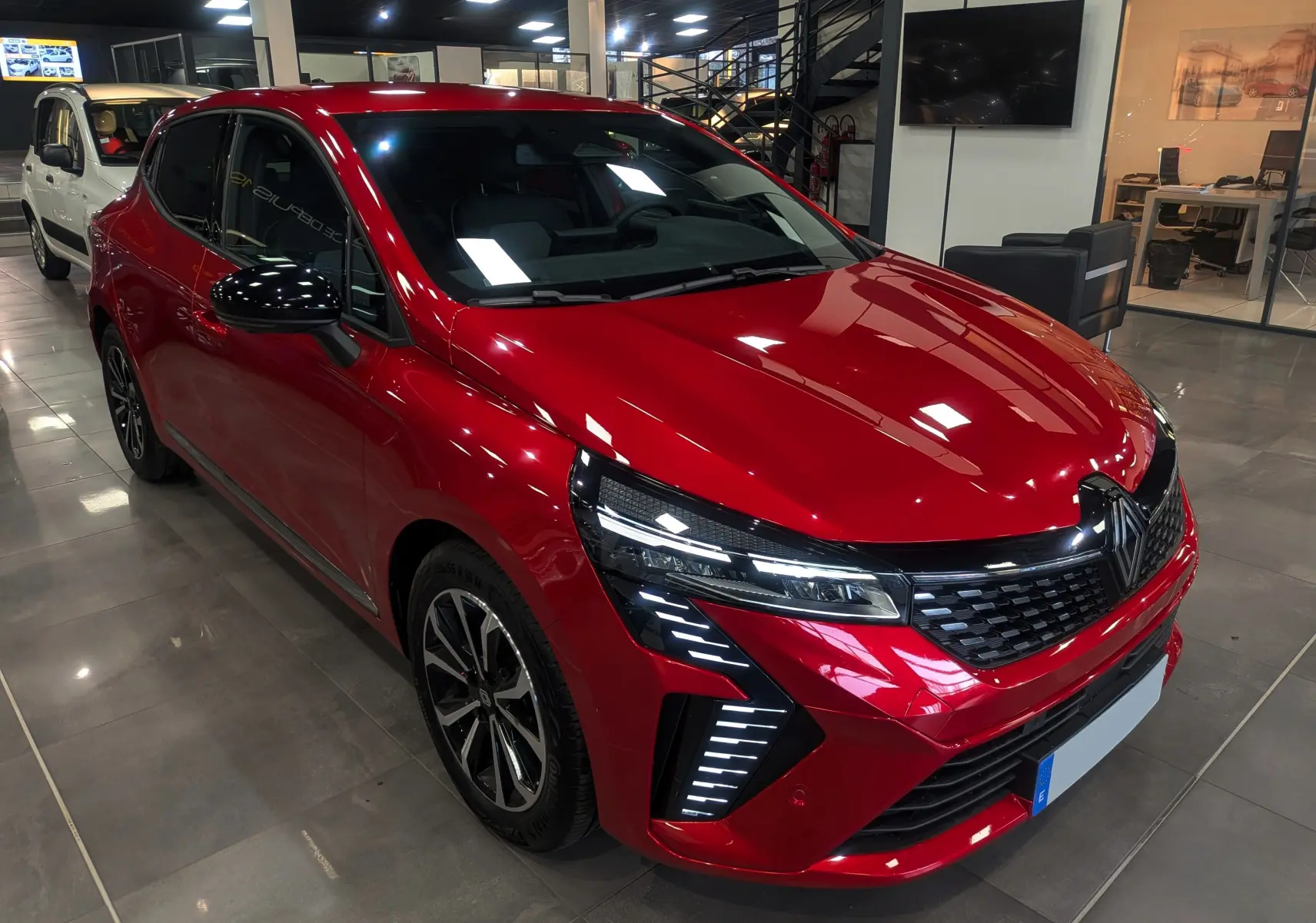 Renault Clio V Rouge Flamme vue 3/4 avant droit, avec feux LED distinctifs et jantes alliage biton.