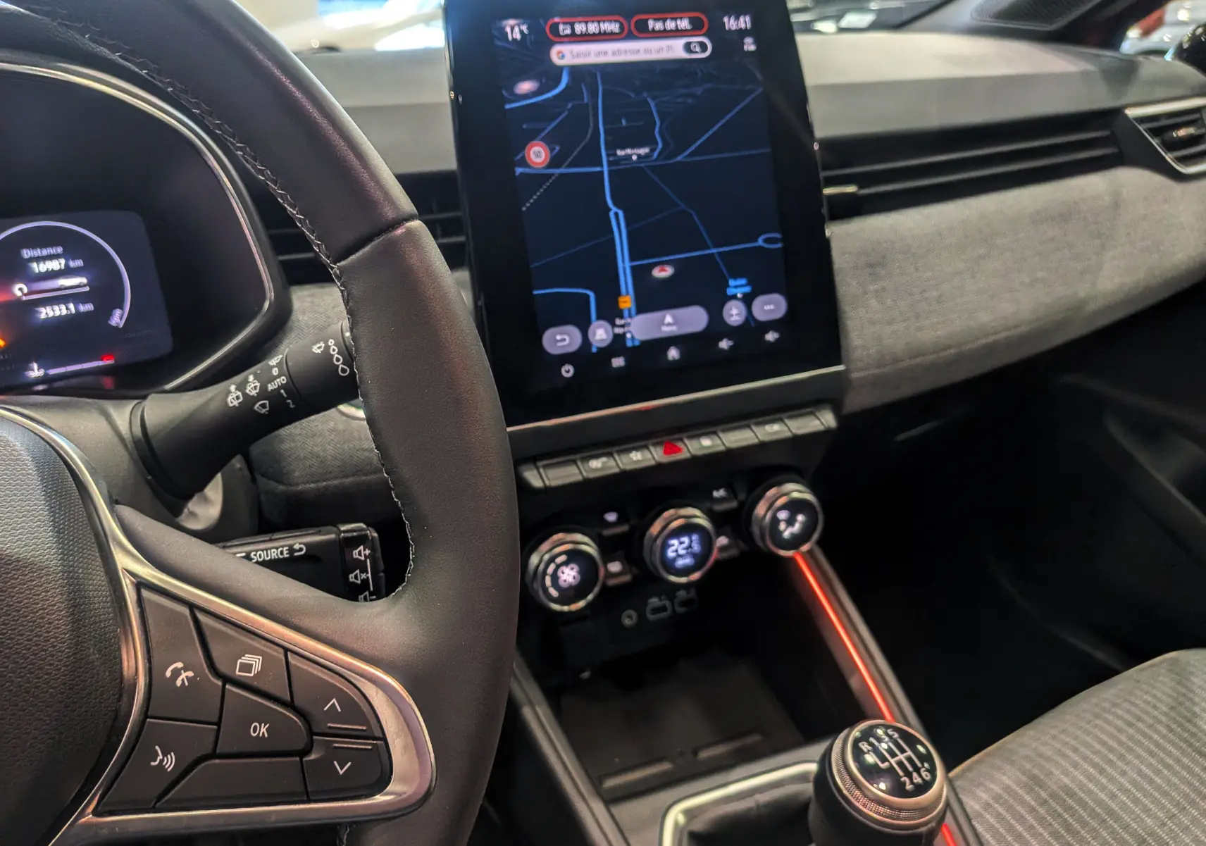 Vue intérieure centrée sur le volant et la console centrale avec écran tactile et levier de vitesse manuel.