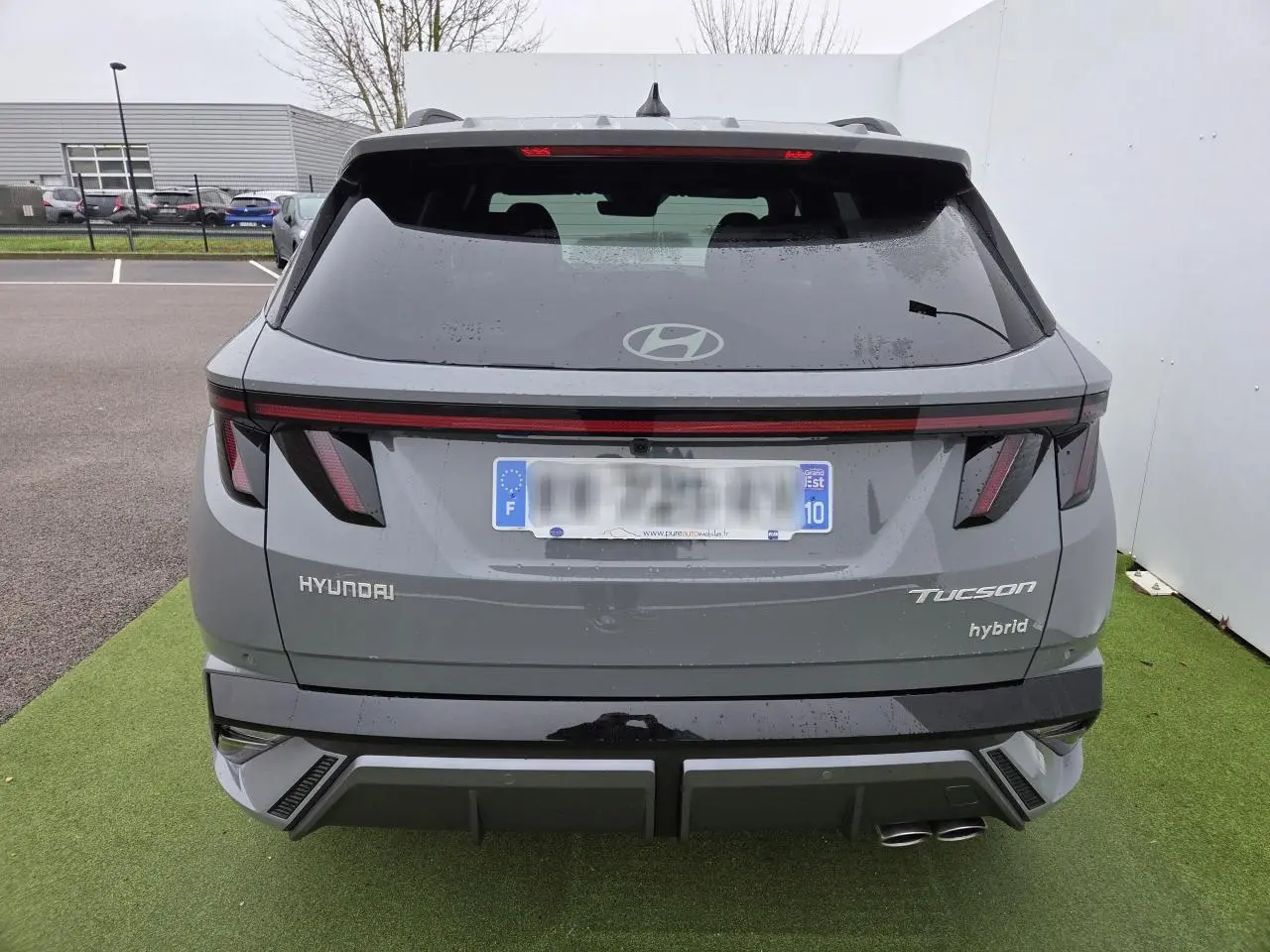 Vue arrière du Hyundai Tucson 2025 gris métallisé avec feux LED et double sortie d'échappement côté droit.