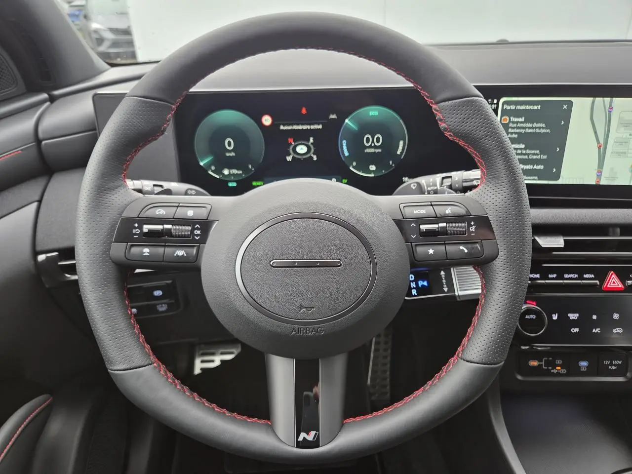 Vue frontale du volant sport cuir noir avec surpiqûres rouges et tableau de bord numérique du Hyundai Tucson N Line 2025.