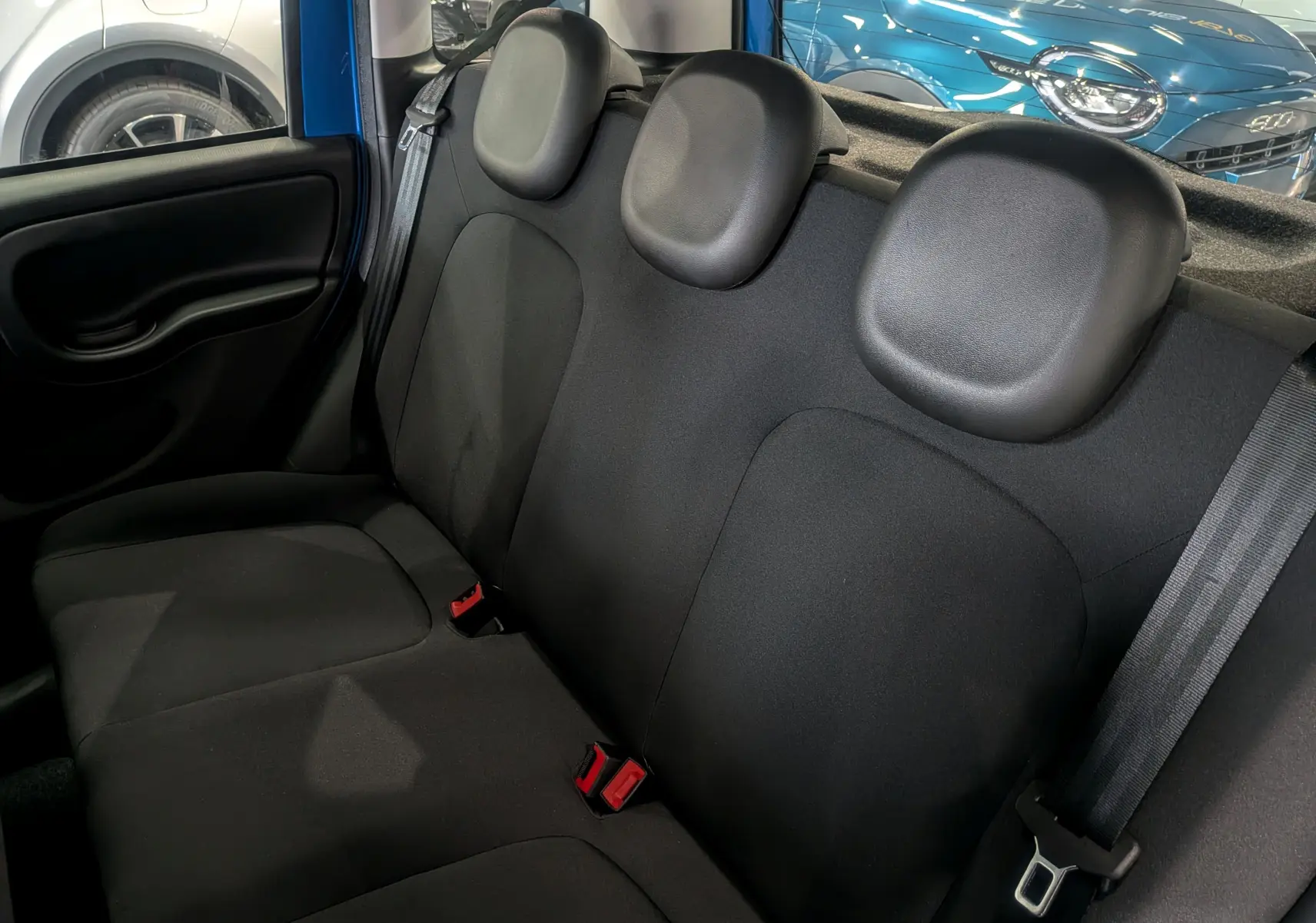 Vue intérieure de la banquette arrière noire de la Fiat Panda 1.0 Hybrid City 2025, avec appuie-têtes et ceinture visible.