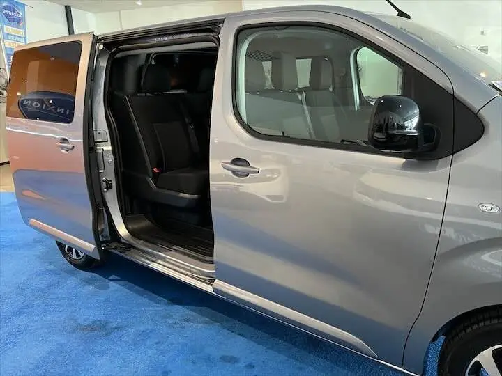 Vue latérale droite du FIAT Scudo cabine approfondie gris Artense métal avec porte coulissante ouverte dévoilant l'intérieur noir.