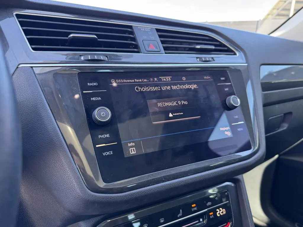 Vue rapprochée de l'écran tactile central du Volkswagen Tiguan gris 2021 avec commandes multimédia et climatisation digitale.