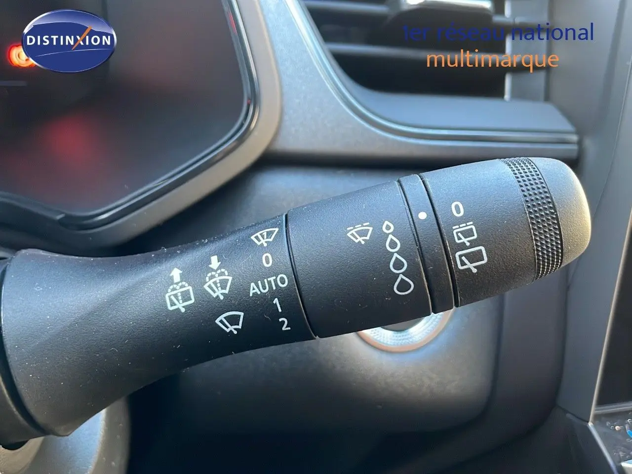 Gros plan sur la commande des essuie-glaces du Renault Captur E-Tech gris Cassiopée, avec symboles blancs visibles.