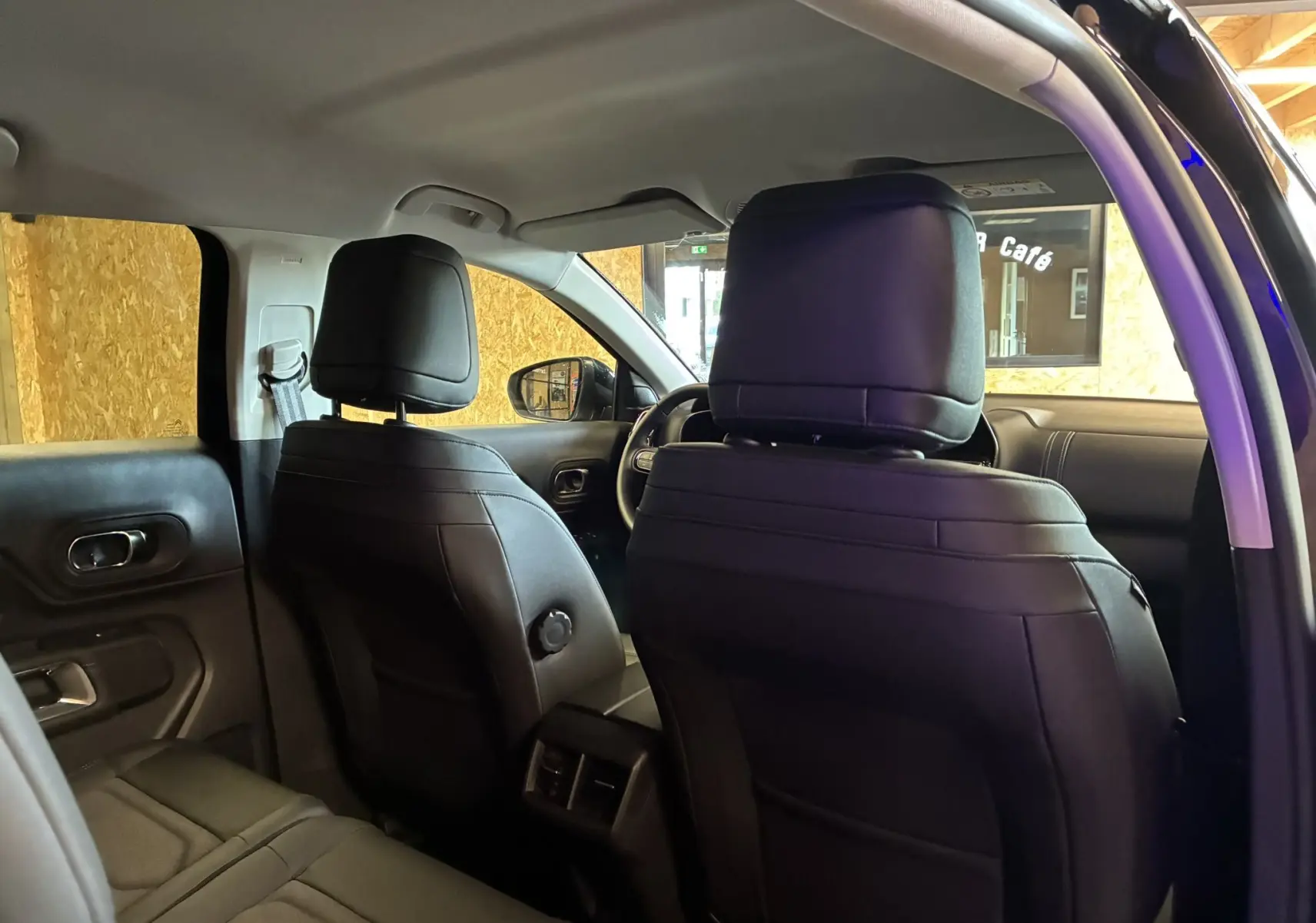 Vue intérieure arrière du Citroën C5 Aircross bleu Eclipse Métal, montrant les sièges avant en cuir noir et la console centrale.