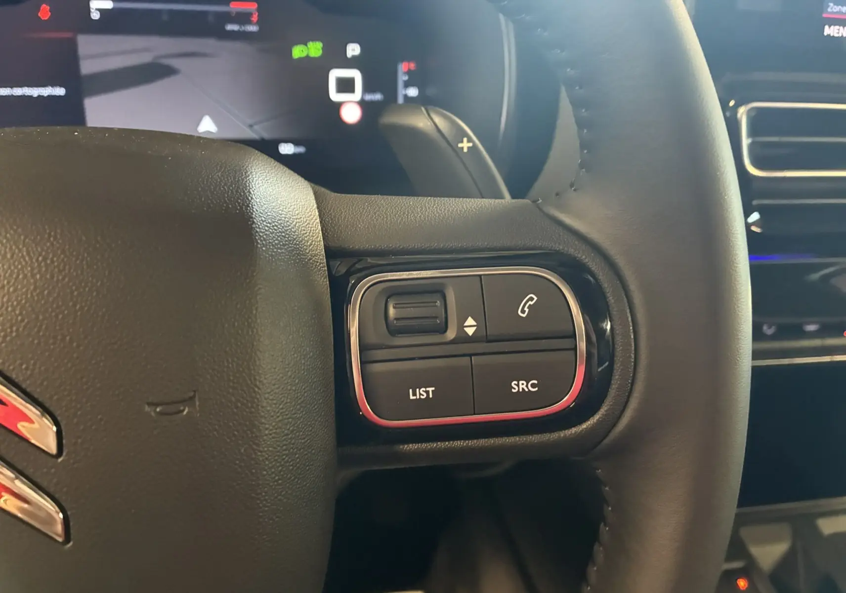 Gros plan sur les commandes à droite du volant en cuir noir du Citroën C5 Aircross 2025, avec écran numérique en arrière-plan.