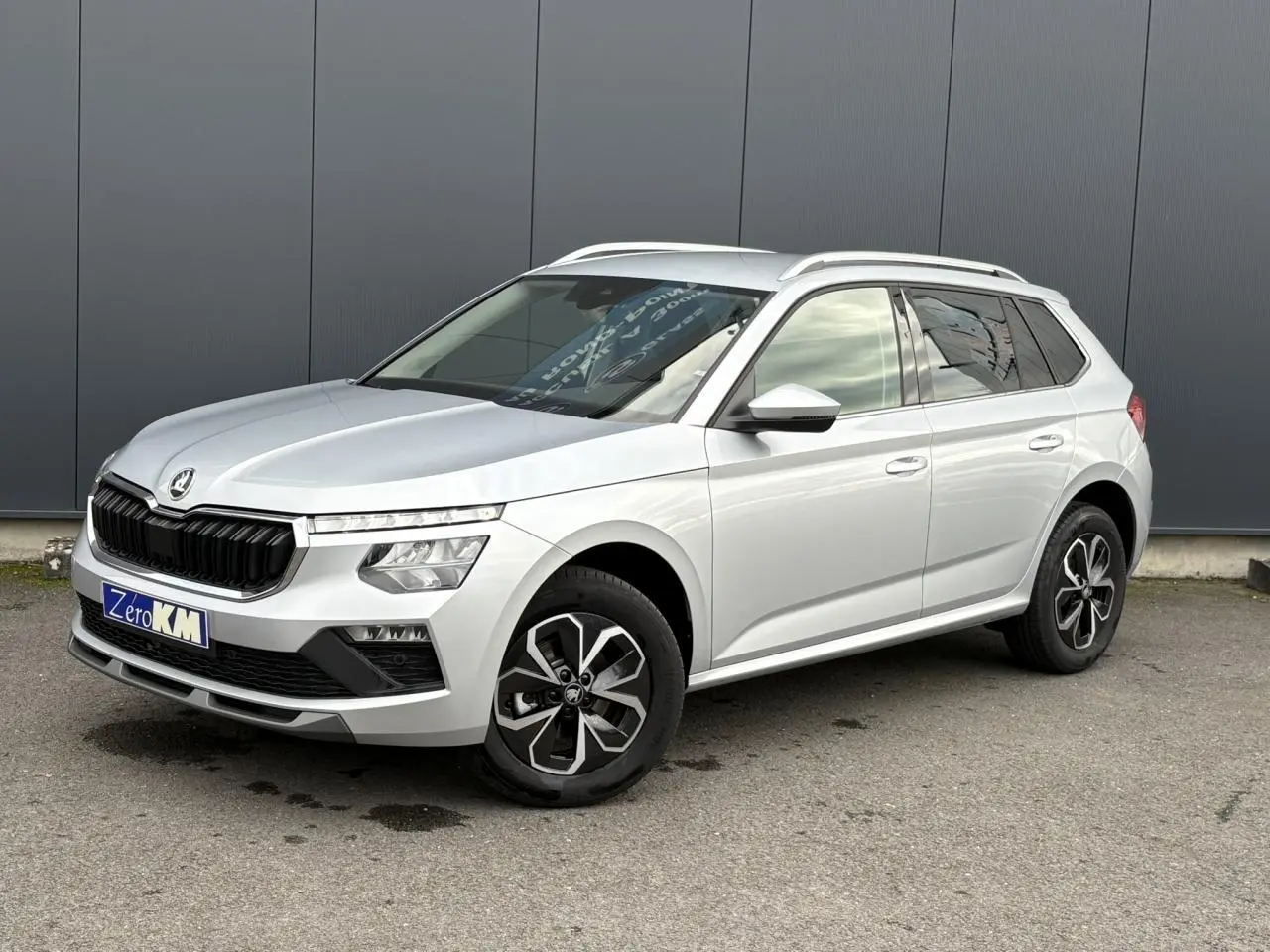 Skoda Kamiq gris argent vu en 3/4 avant droit avec jantes alliage et vitres surteintées.