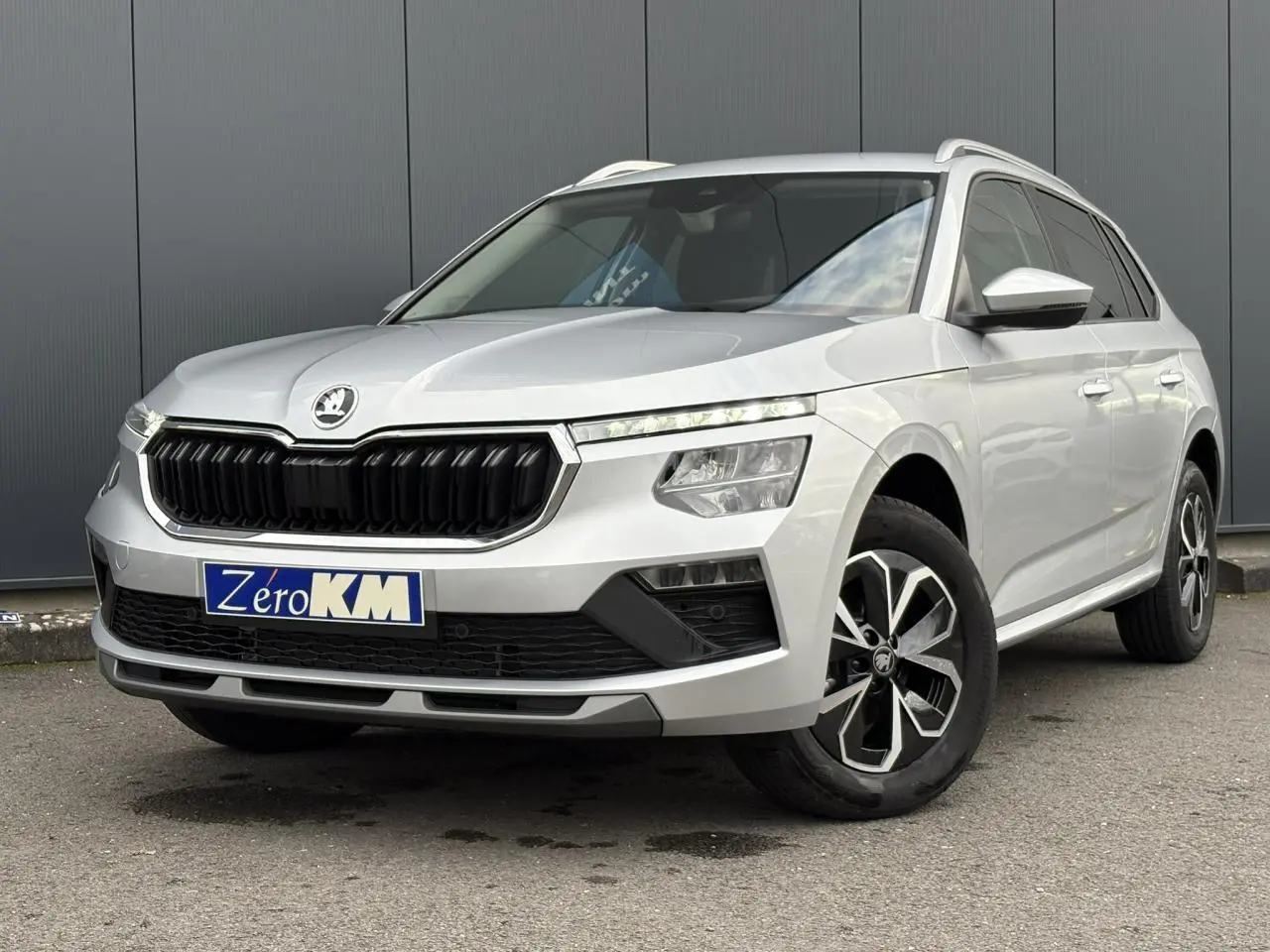 Vue 3/4 avant droite d'un Skoda Kamiq gris argent avec calandre noire et jantes alliage distinctives.