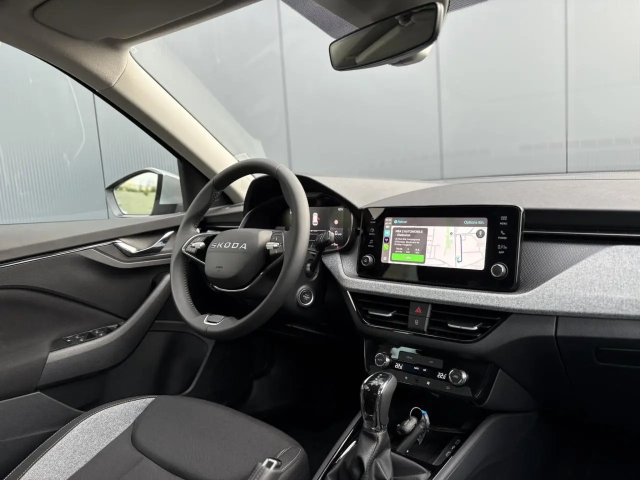 Intérieur du Skoda Kamiq 2025 vu côté conducteur, tableau de bord gris avec écran tactile et volant multifonctions.
