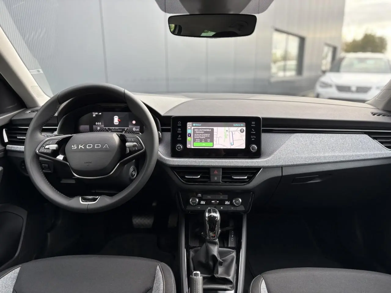 Vue frontale de l'intérieur du Skoda Kamiq gris argent, avec volant multifonctions et écran tactile central allumé.