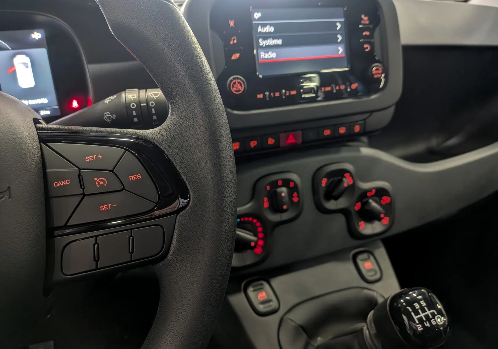 Vue intérieure centrée sur le volant et la console centrale d'une Fiat Panda 1.0 Hybrid 2025 avec boîte manuelle.