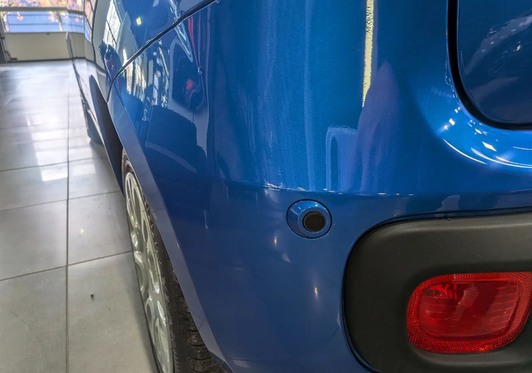 Gros plan sur l’aile arrière droite bleu Italia d’une Fiat Panda 1.0 Hybrid 2025, avec feu arrière et capteur de stationnement visible.