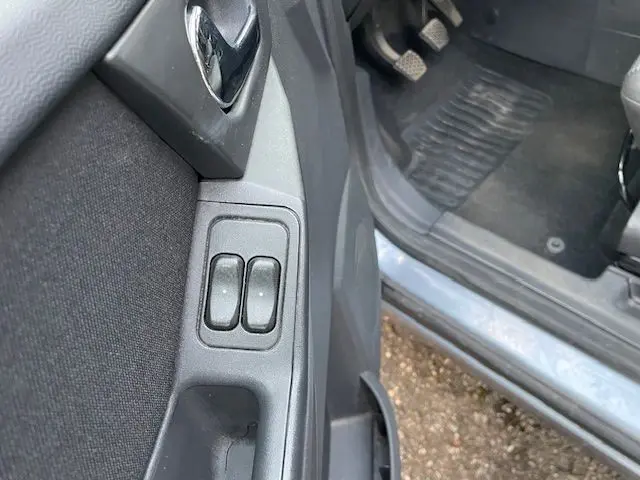 Vue rapprochée des commandes des vitres électriques sur la porte côté gauche d’une Opel Meriva grise de 2010.