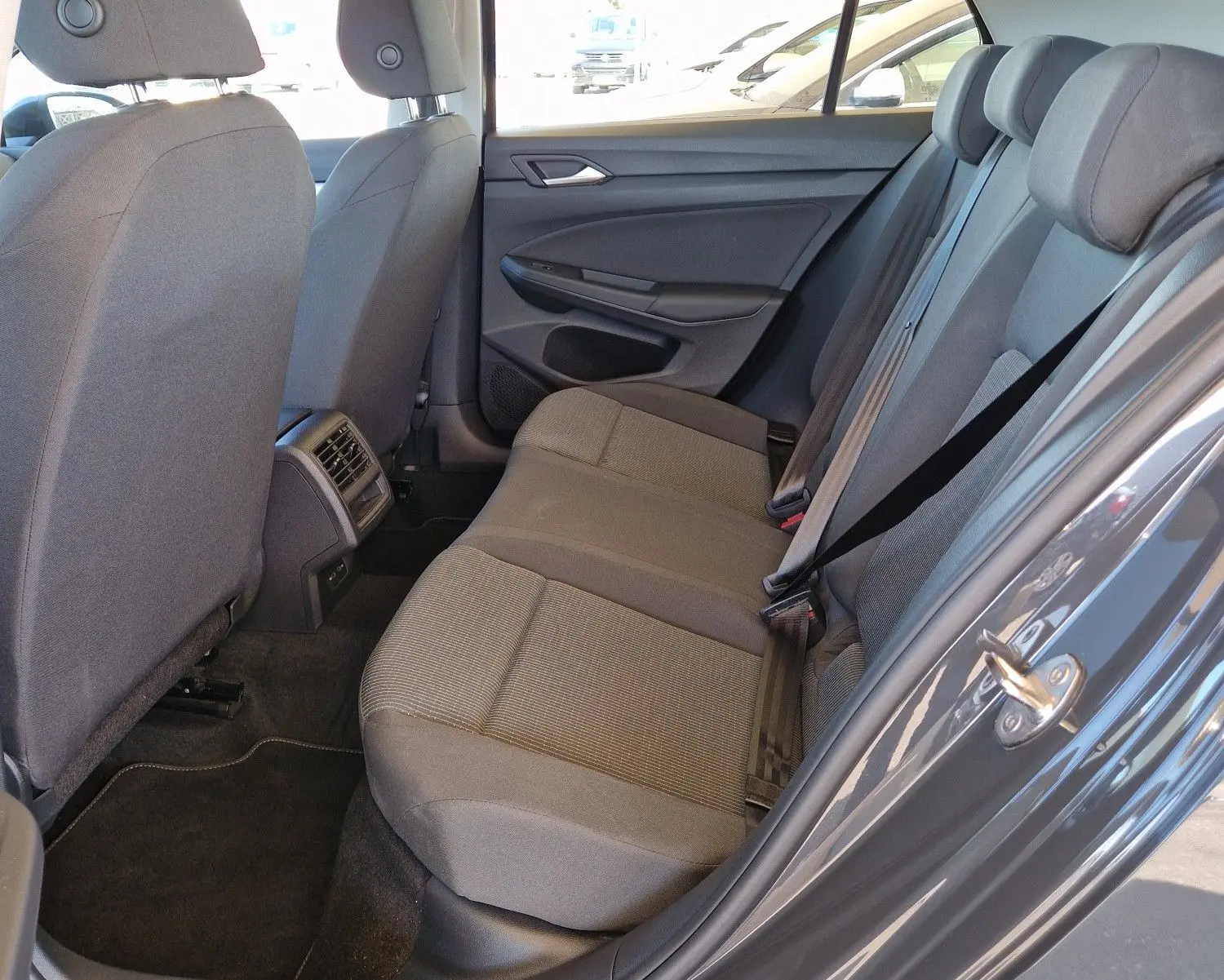 Vue côté droit de l'intérieur arrière gris d'une Volkswagen Golf A8 2023 avec sièges tissu et aérateurs centraux.