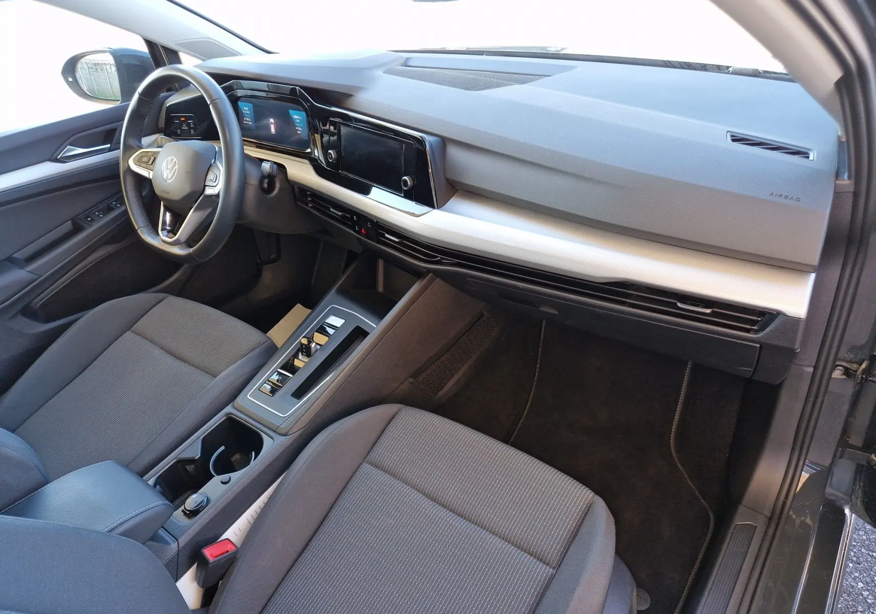 Intérieur côté conducteur de la Volkswagen Golf A8 gris Urano 2023, tableau de bord moderne avec écran tactile et volant multifonction.