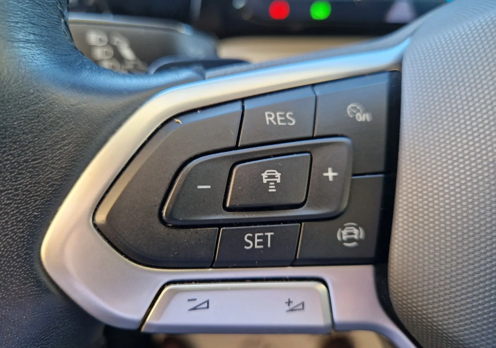 Gros plan sur les commandes du régulateur de vitesse au volant d'une Volkswagen Golf A8 2023, finition gris Urano.