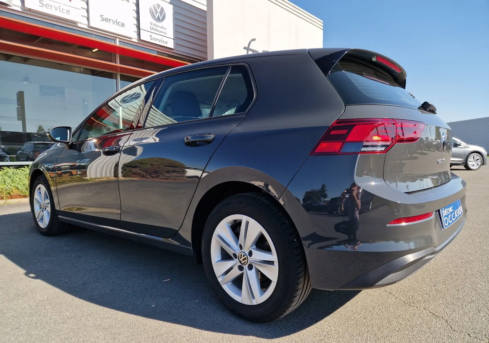 Volkswagen Golf A8 gris Urano vue 3/4 arrière côté gauche, avec jantes alliage et feux arrière LED.