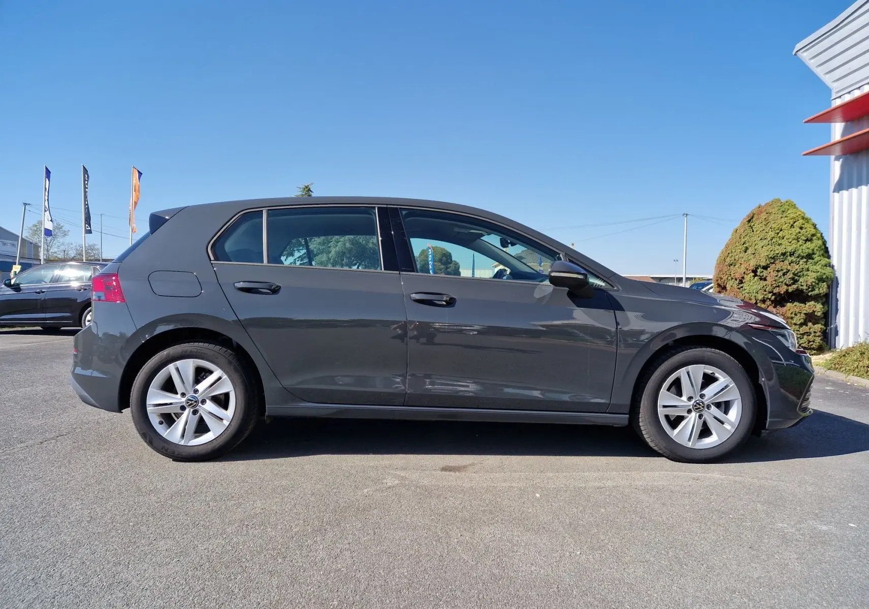 Profil côté gauche d'une Volkswagen Golf A8 2023 gris Urano, avec jantes alliage et lignes épurées visibles.