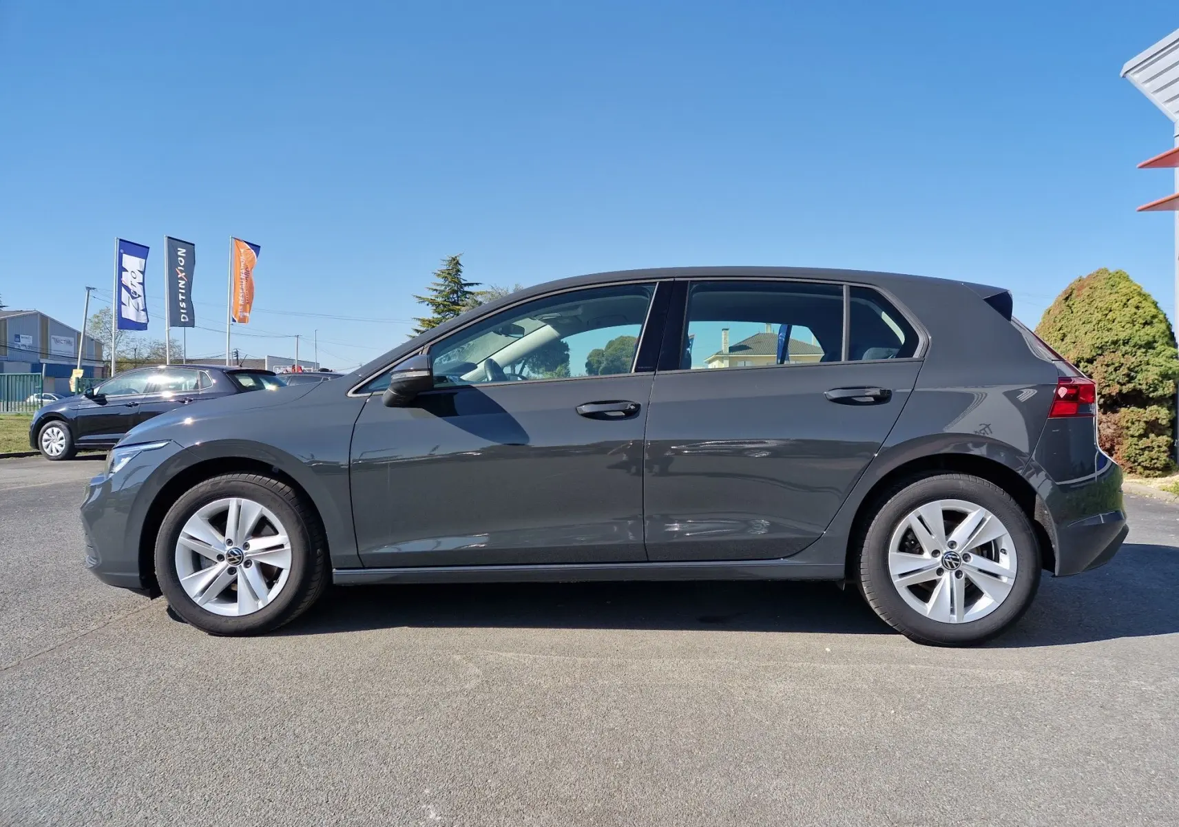 Profil droit d'une Volkswagen Golf A8 gris Urano 2023, avec jantes alliage et lignes épurées visibles.