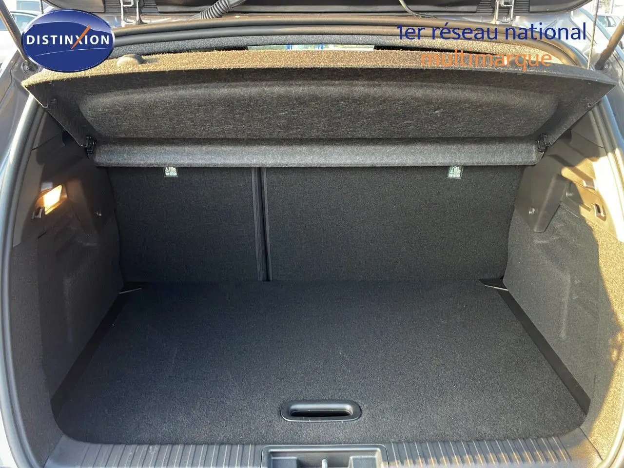 Coffre ouvert vu de l'arrière du Renault Captur E-Tech hybride gris Cassiopée, montrant un espace de chargement propre et spacieux.