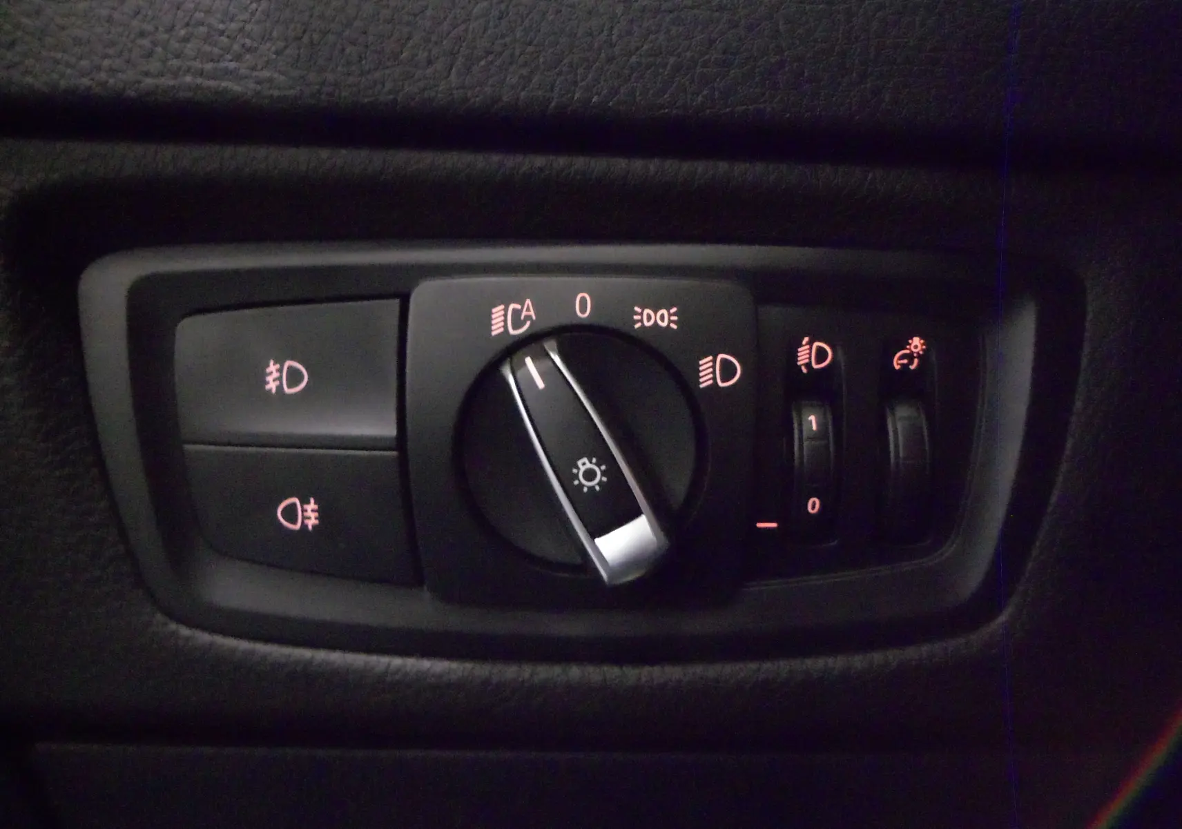 Gros plan sur le panneau de commande des phares de la BMW Série 1 F21 LCI 118i gris, avec réglages lumineux éclairés.