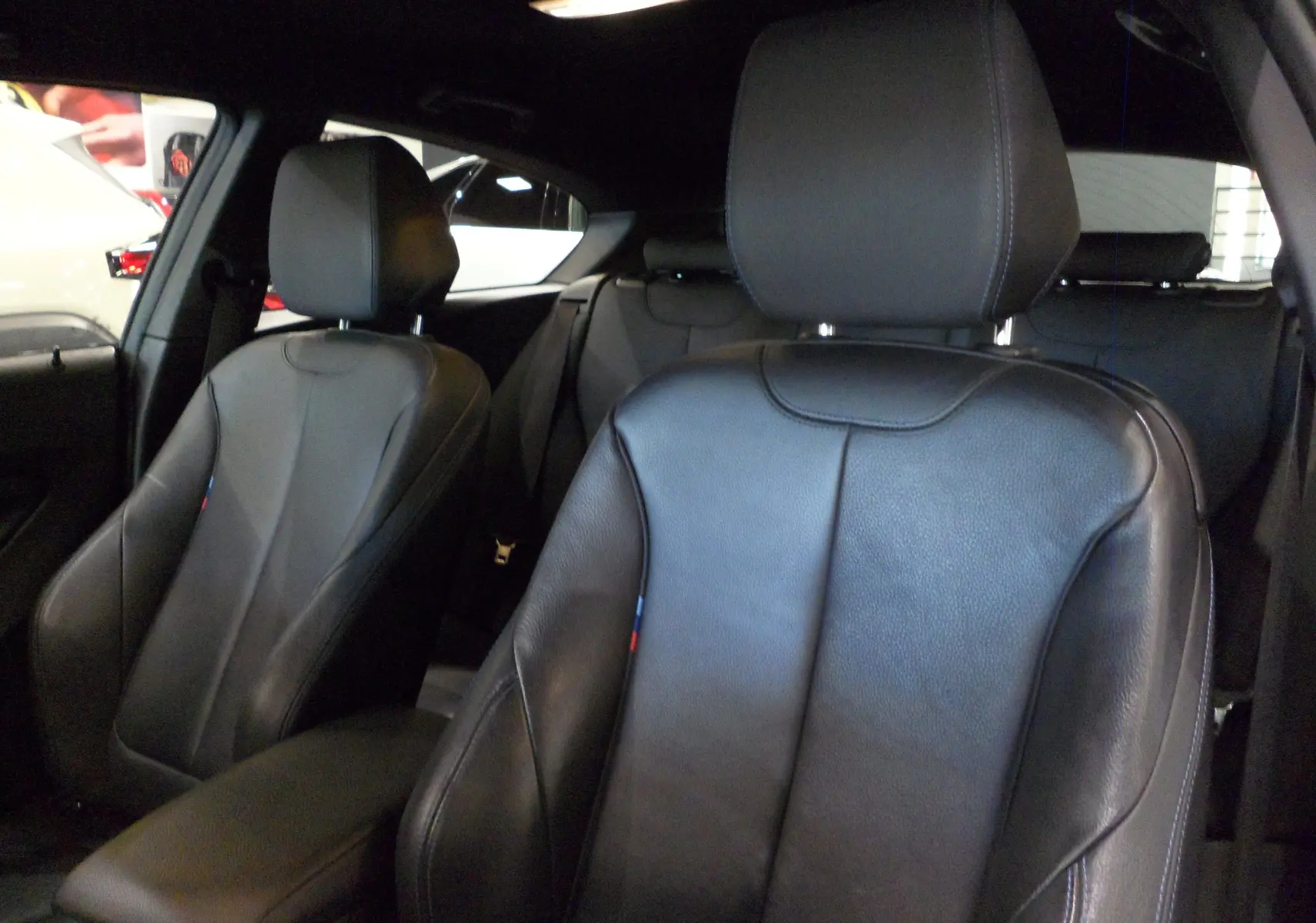 Gros plan sur les sièges avant en cuir noir de la BMW Série 1 F21 LCI gris, version 118i M Sport Ultimate.