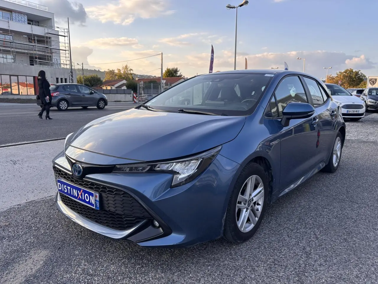 Toyota Corolla hybride bleu clair vue 3/4 avant droit avec calandre noire et jantes argentées.