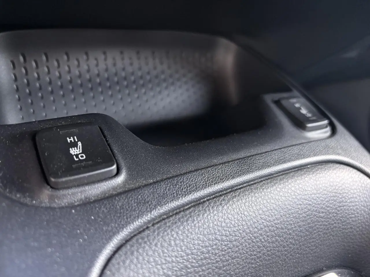 Bouton de réglage de siège chauffant en gros plan dans l'habitacle noir d'une Toyota Corolla Hybride 2020.
