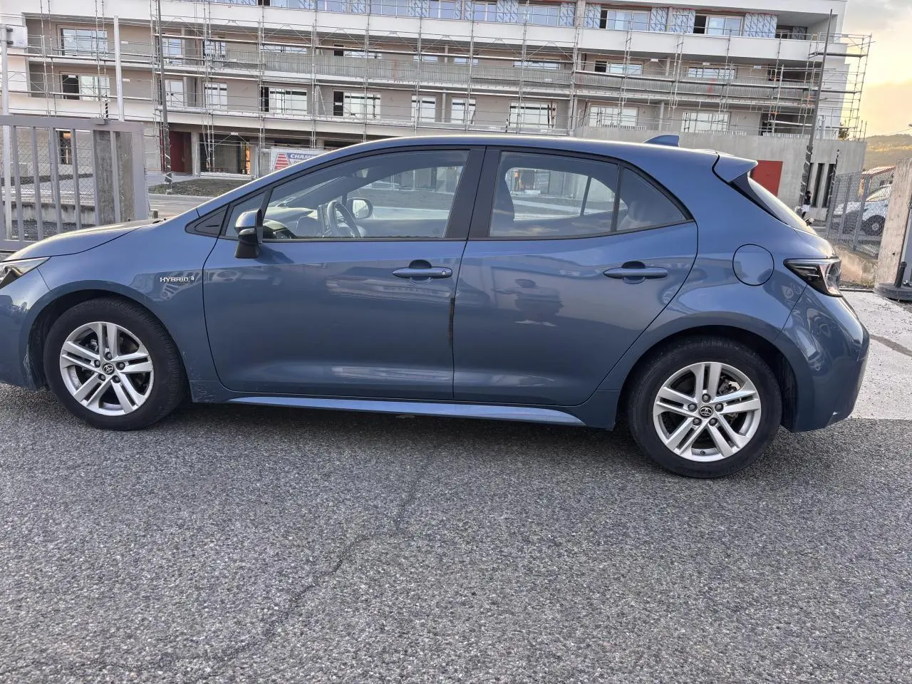 Profil côté gauche d'une Toyota Corolla hybride 2020 bleu clair, berline compacte avec jantes alliage et badge Hybrid visible.