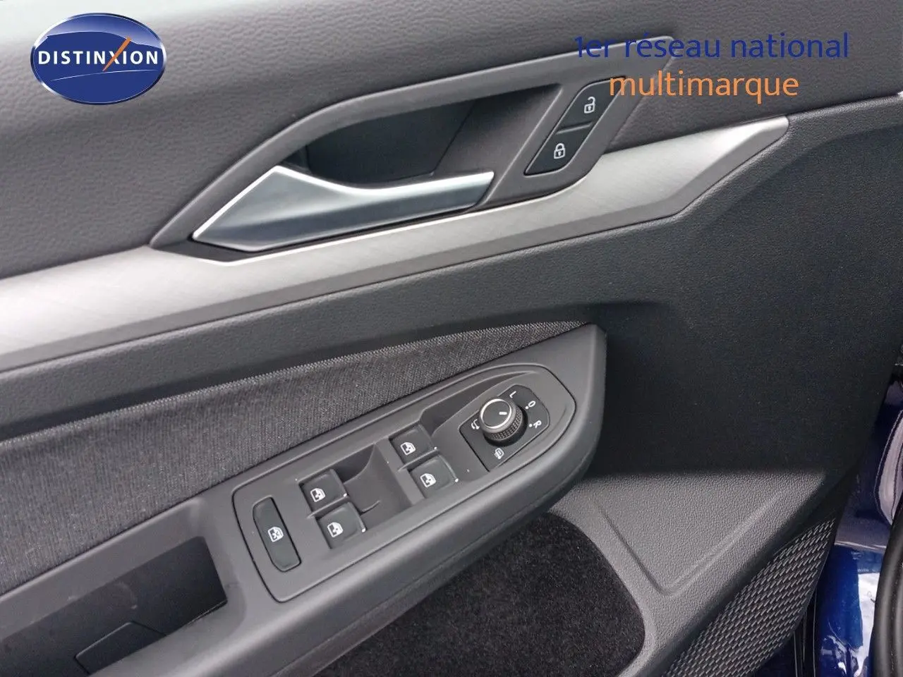 Gros plan sur la porte côté conducteur de la Volkswagen Golf VIII bleu Atlantique, montrant les commandes des vitres et rétroviseurs.