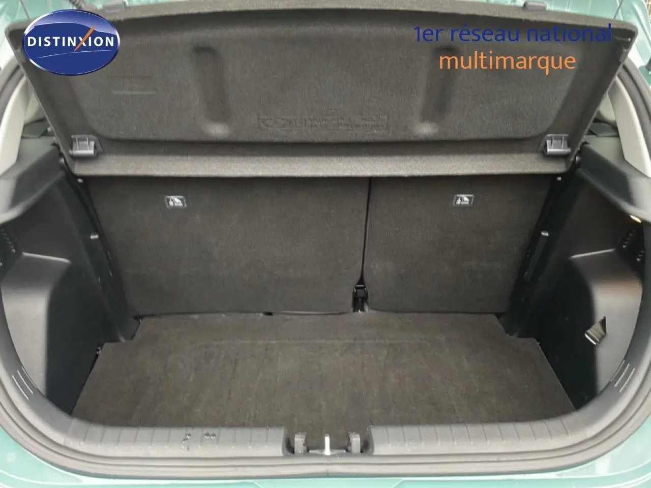 Coffre ouvert vu de l'arrière d'une Hyundai i20 2025 vert mangrove metal, montrant l'espace de chargement vide.