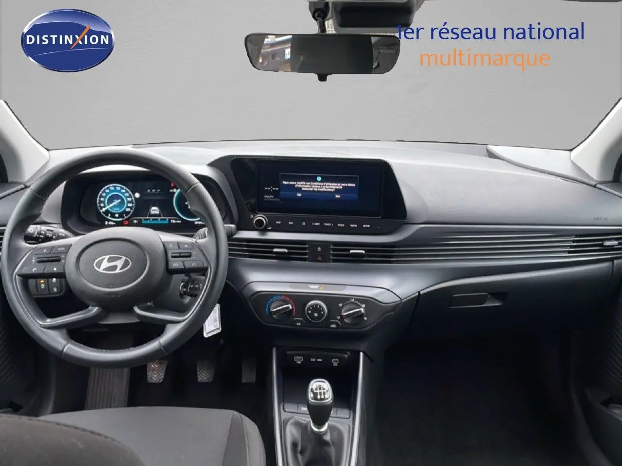 Intérieur de la Hyundai i20 2025, vue frontale du tableau de bord avec volant cuir et écran tactile central.